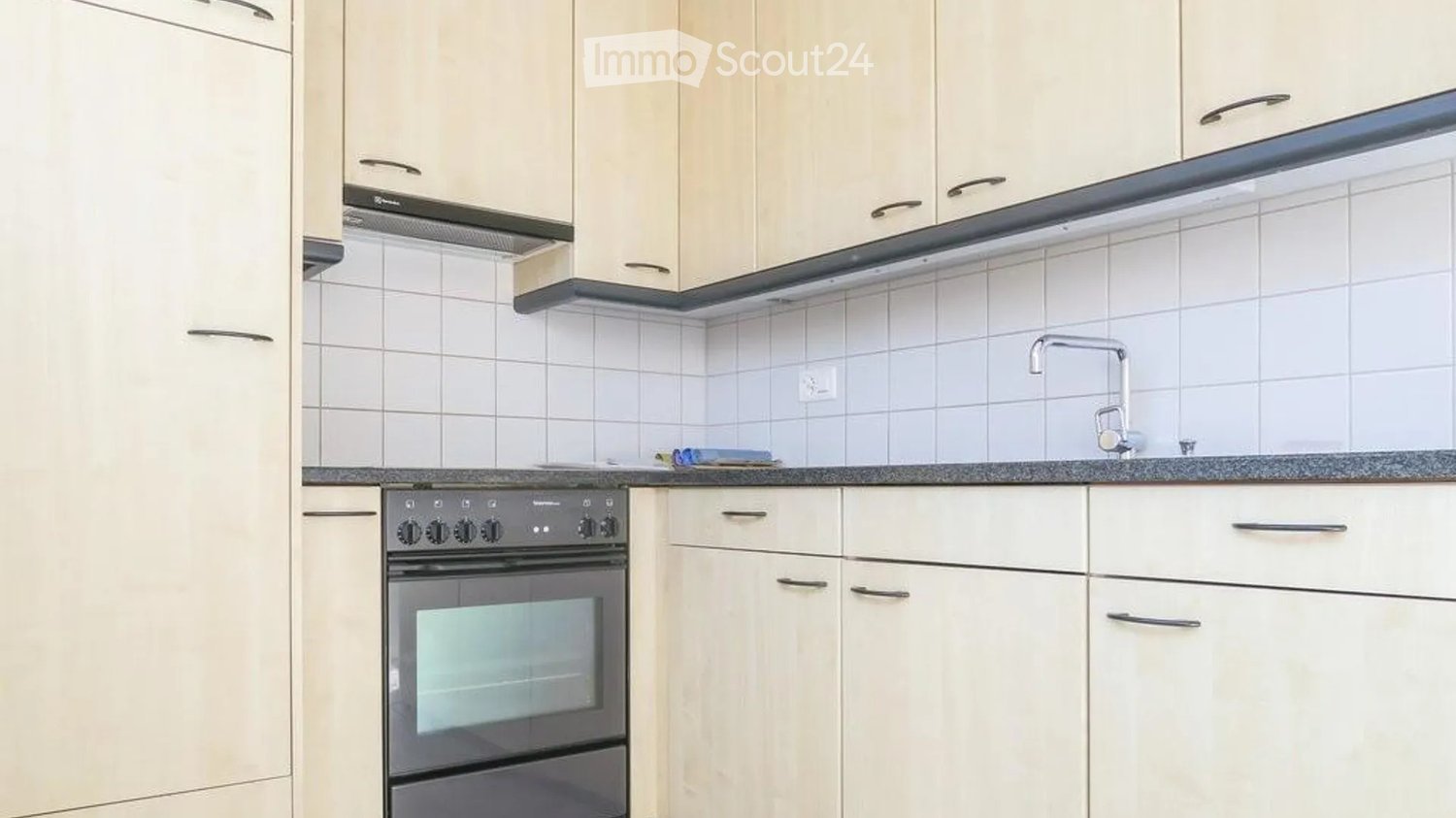 Modern kitchen with white cabinets, a built-in oven, and a tiled backsplash. A faucet is visible on the countertop.