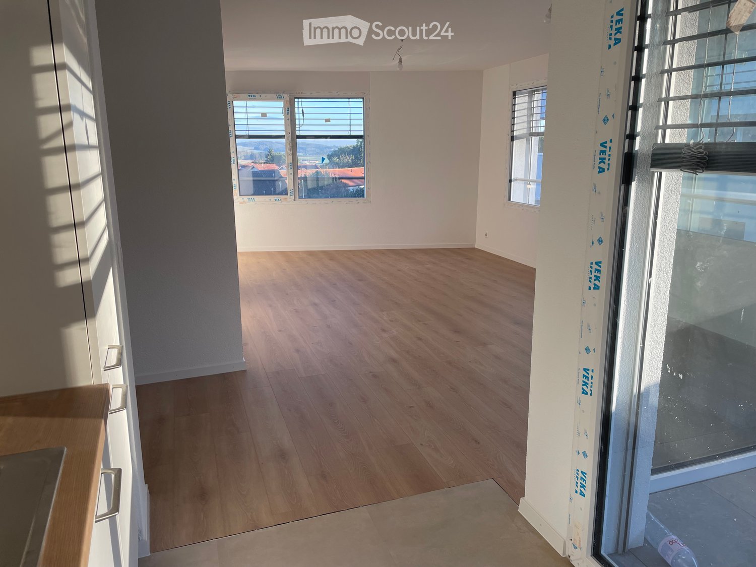 Empty room with wooden flooring, white walls, and large windows offering a scenic view. No furniture or equipment is present.