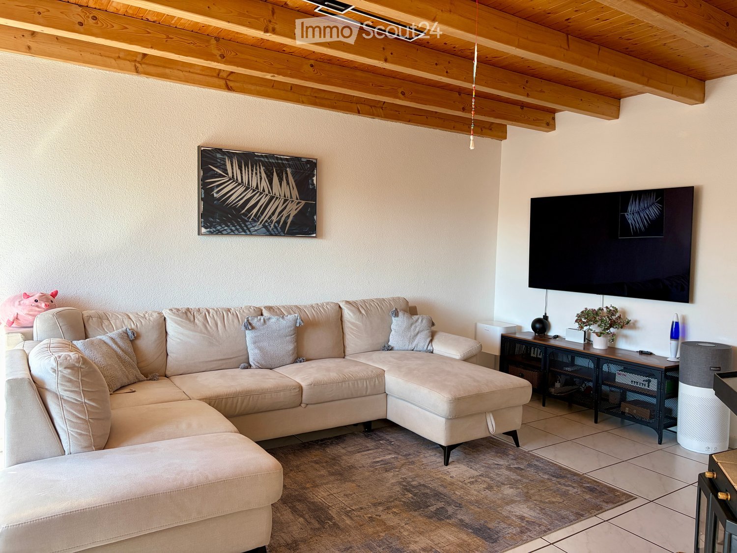 Modern living room with a large sectional sofa, coffee table, wall-mounted TV, and decorative items.
