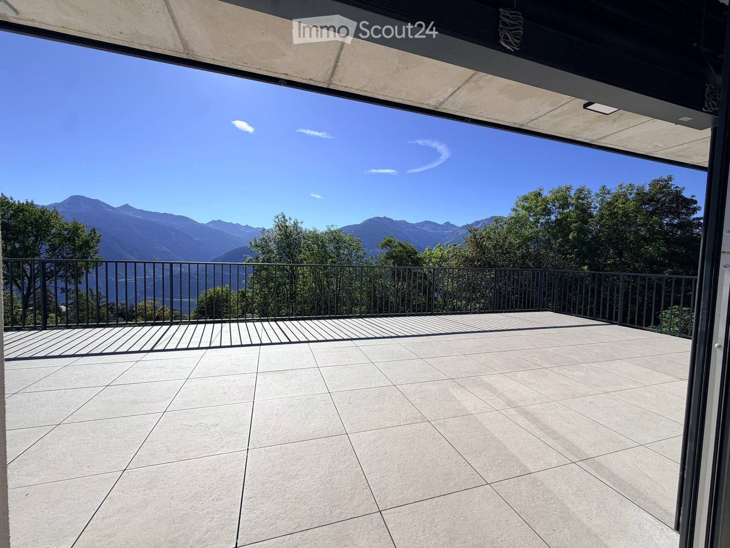 Balcony with tiled floor, metal railing, and scenic mountain view.