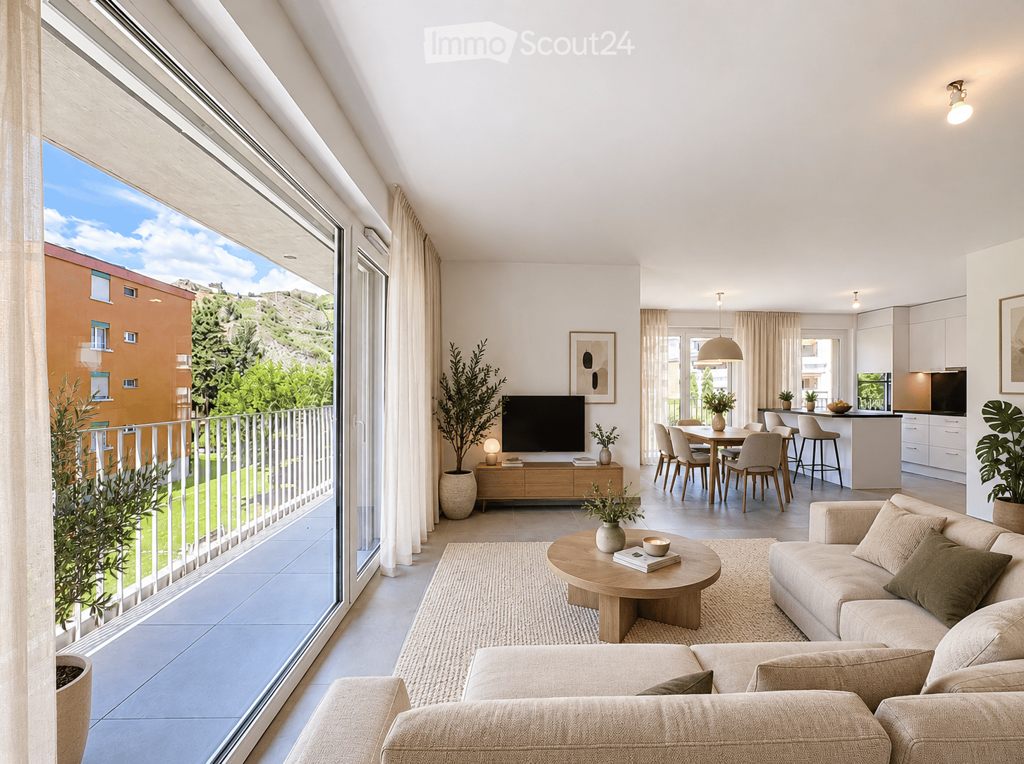 Modern, open-concept living and dining area with large windows offering a scenic view, featuring a beige sofa, wooden coffee table, flat-screen TV, dining table with chairs, and a sleek kitchen island.
