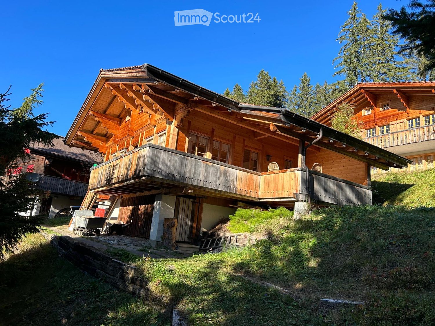 Wooden chalet, wooden balcony, sloped roof, green surroundings, trees