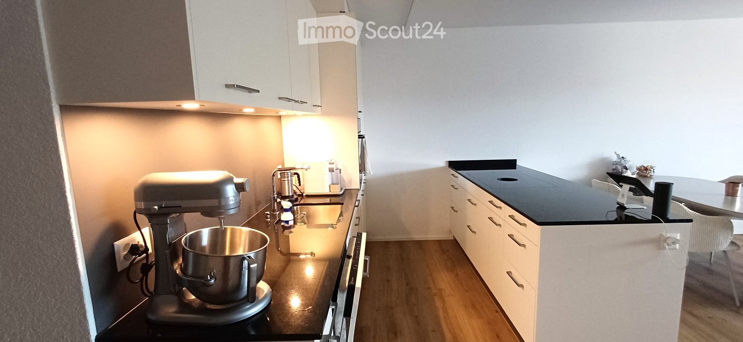 Modern kitchen with white cabinets, black countertops, a mixer, and a sink.