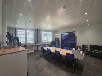 Conference room with a long table, chairs, and a large screen for presentations.