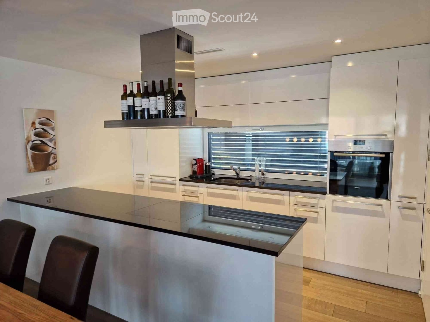 Central island, white cabinets, black countertops, integrated dishwasher, wine rack, modern appliances