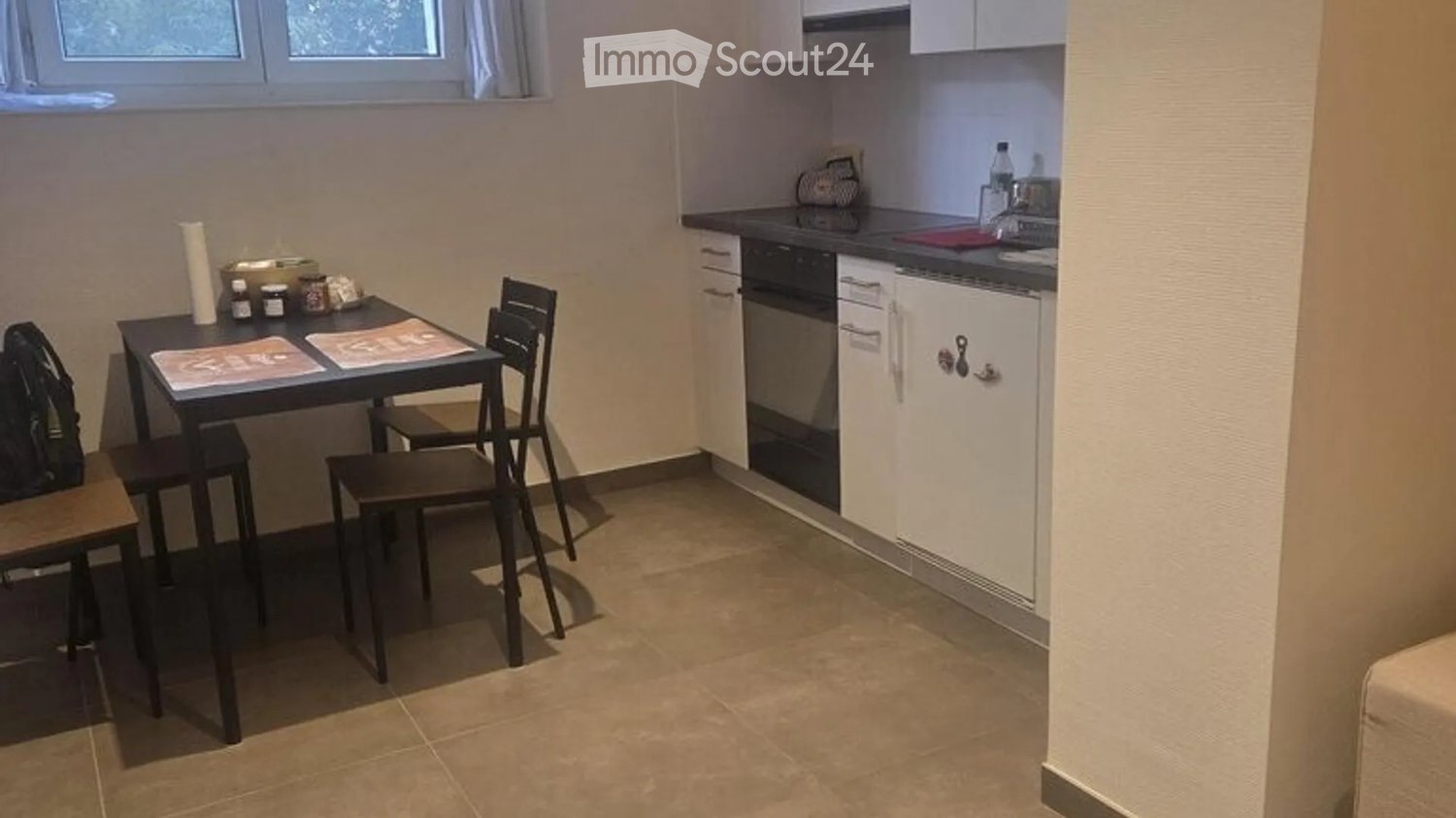 Compact kitchen with a small dining area, featuring a table, chairs, oven, dishwasher, and white cabinets.