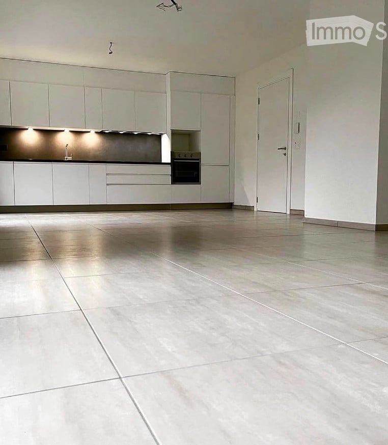 Empty kitchen with white cabinets, stainless steel appliances, and tiled floor. No furniture or equipment present.