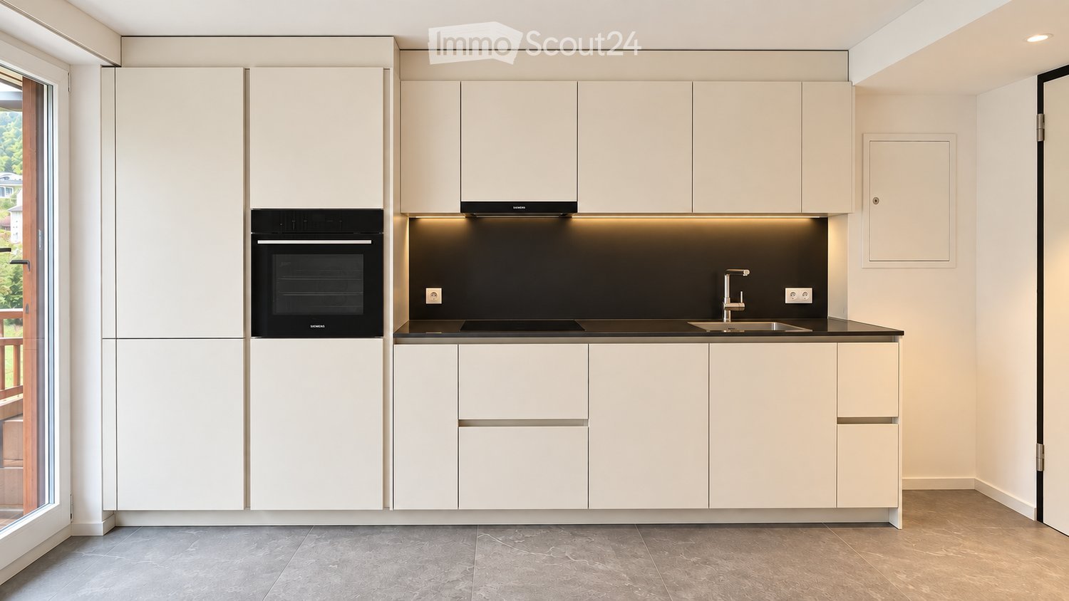 Modern kitchen with white cabinets, a built-in oven, a sink with a modern faucet, and sleek countertops.