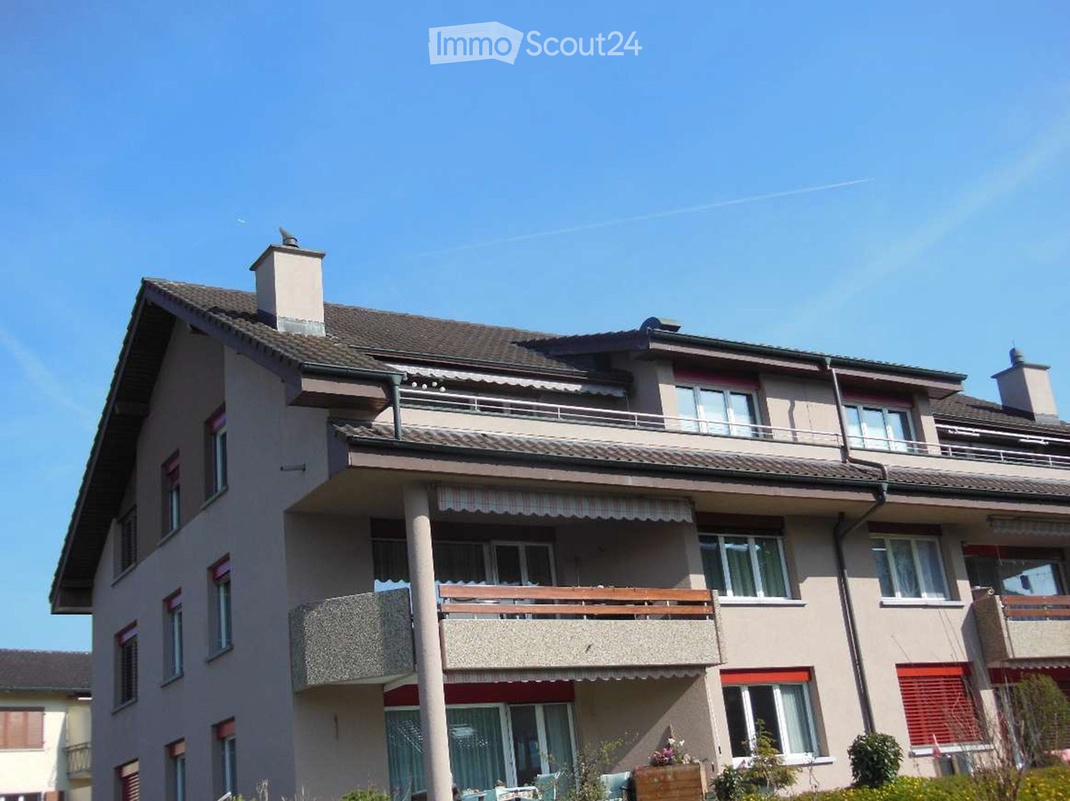 Multi-story residential building with balconies, chimneys, and multiple windows.