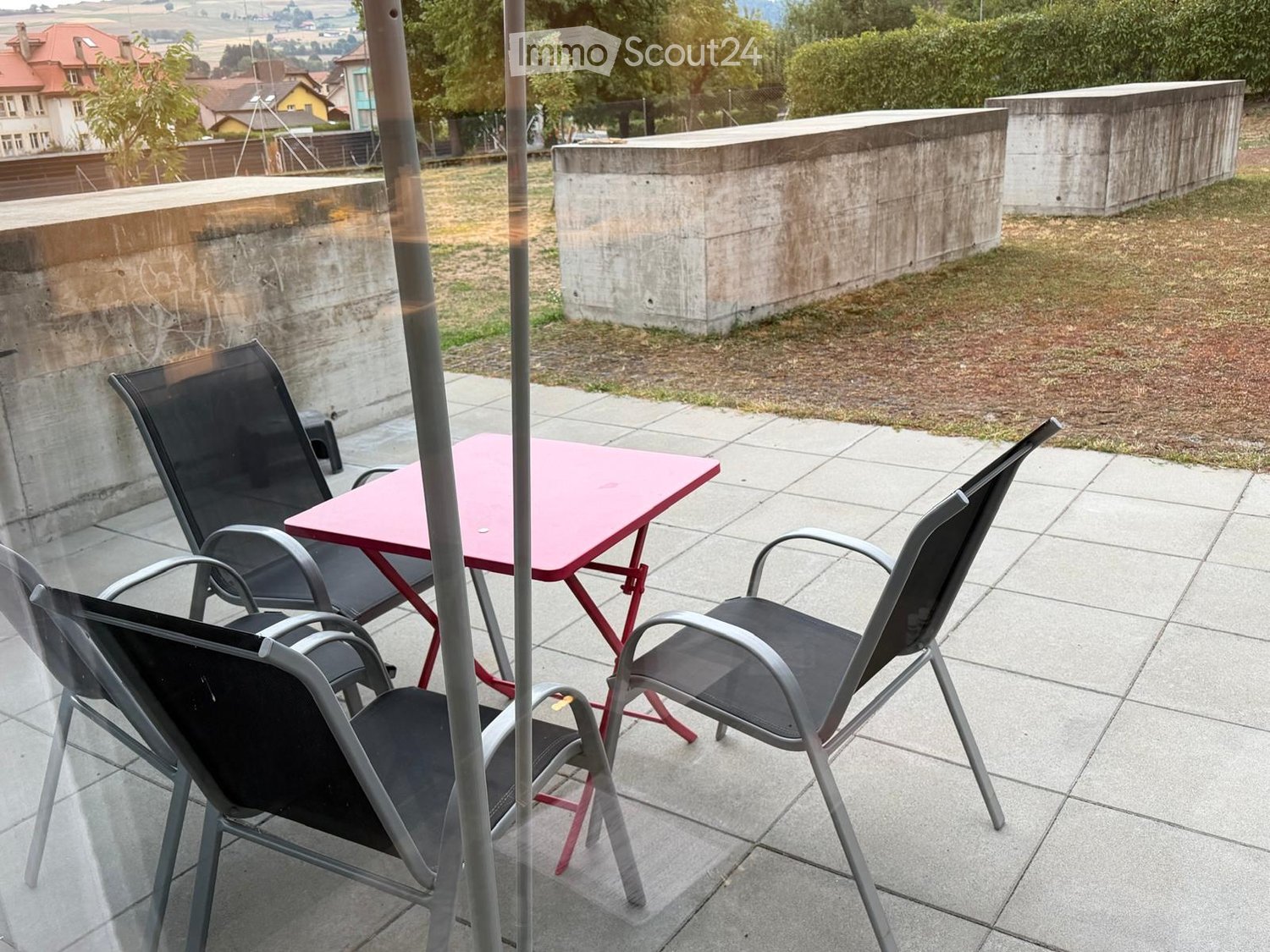 Balcony with tiled floor, pink table, and two black chairs.