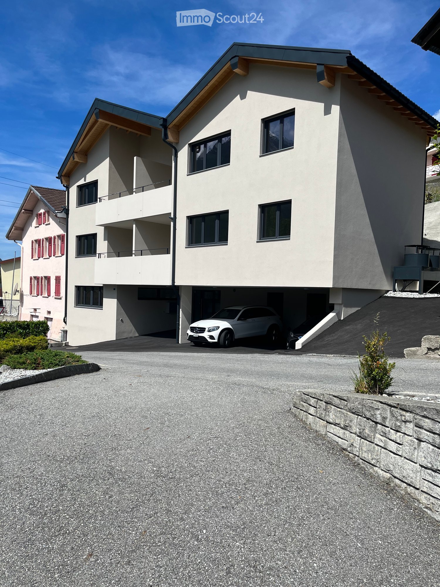 3 story apartment building, white exterior, red shutters, car parked in garage
