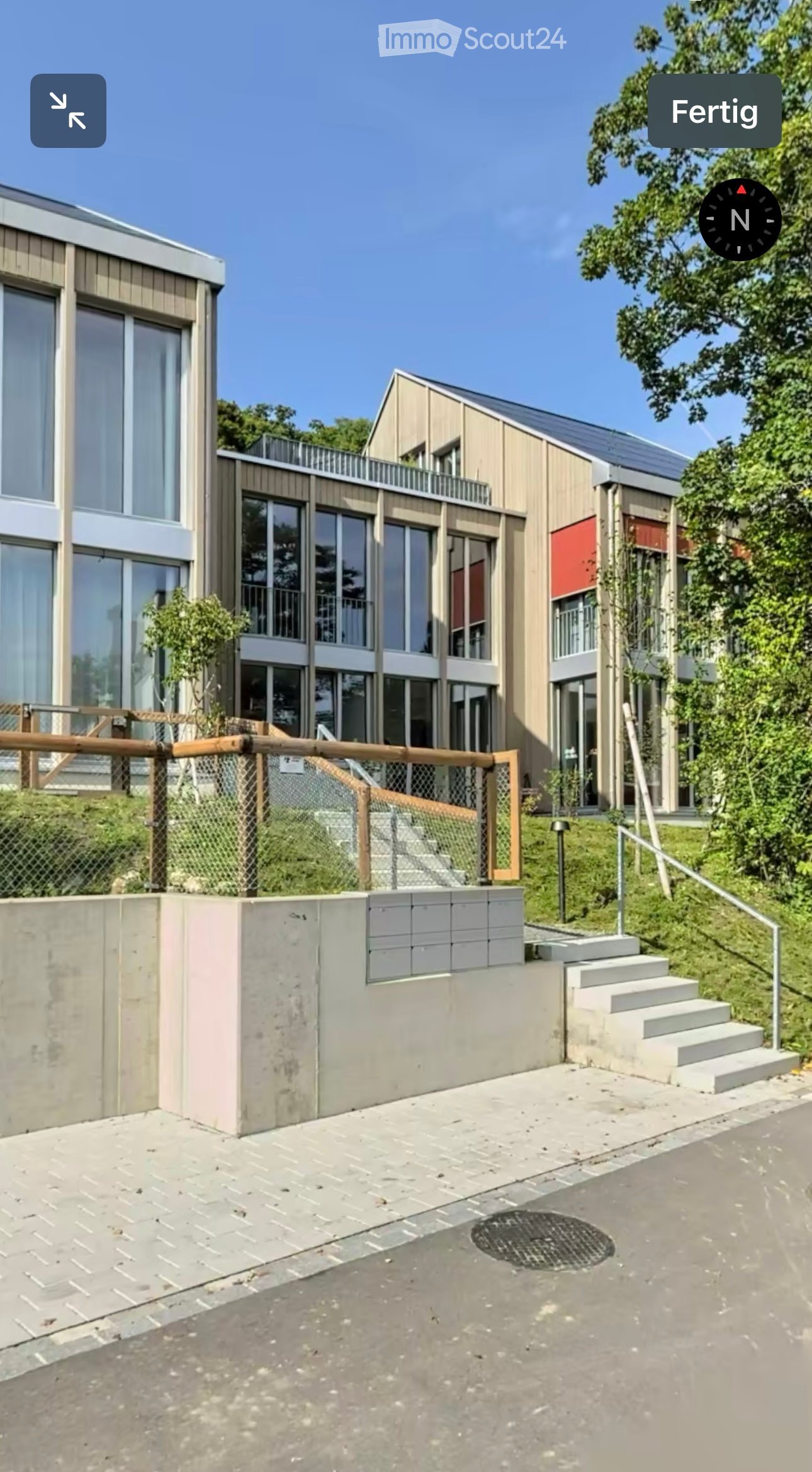 Modern two-story building with large windows, wooden facade, and a raised ground floor accessed by stairs.