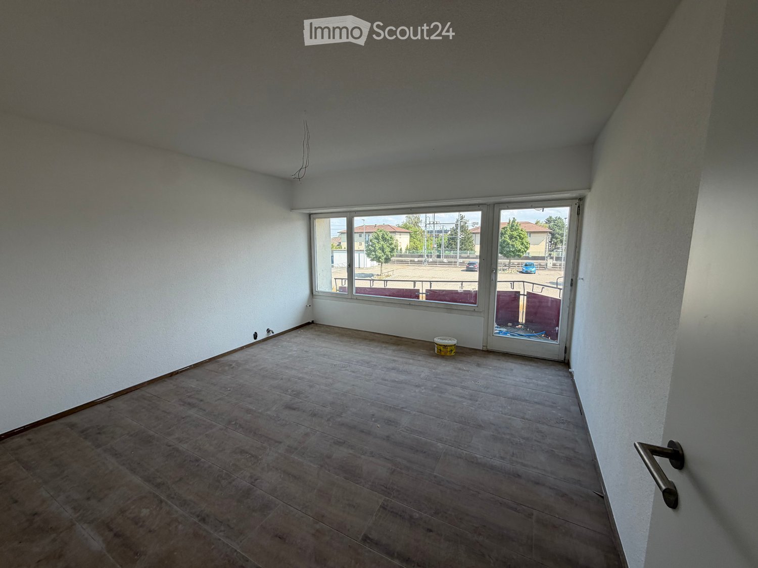 Empty room with tiled floor, white walls, large windows, and a sliding glass door leading to an outdoor area.