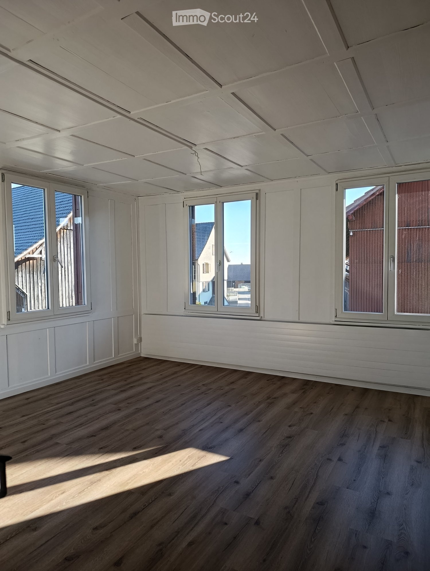 empty room, hardwood floors, 3 large windows, white walls and ceiling, sunny