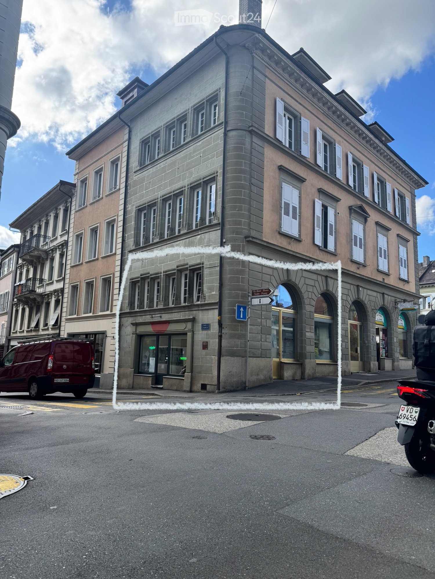 Multi-story building with classic architecture, arched entrance, and multiple windows with shutters.