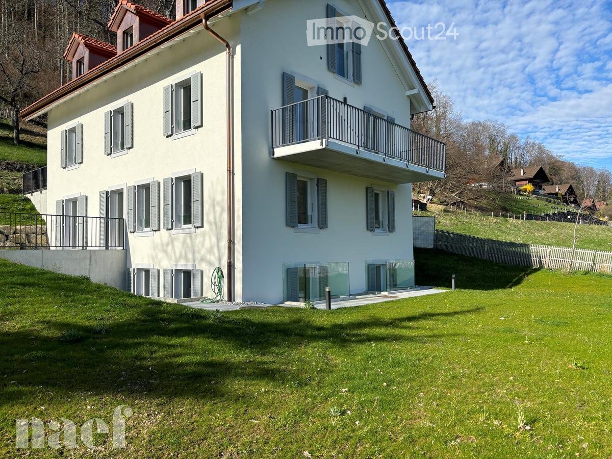 Two-story house with white exterior, multiple windows with shutters, balconies, and a well-maintained lawn.