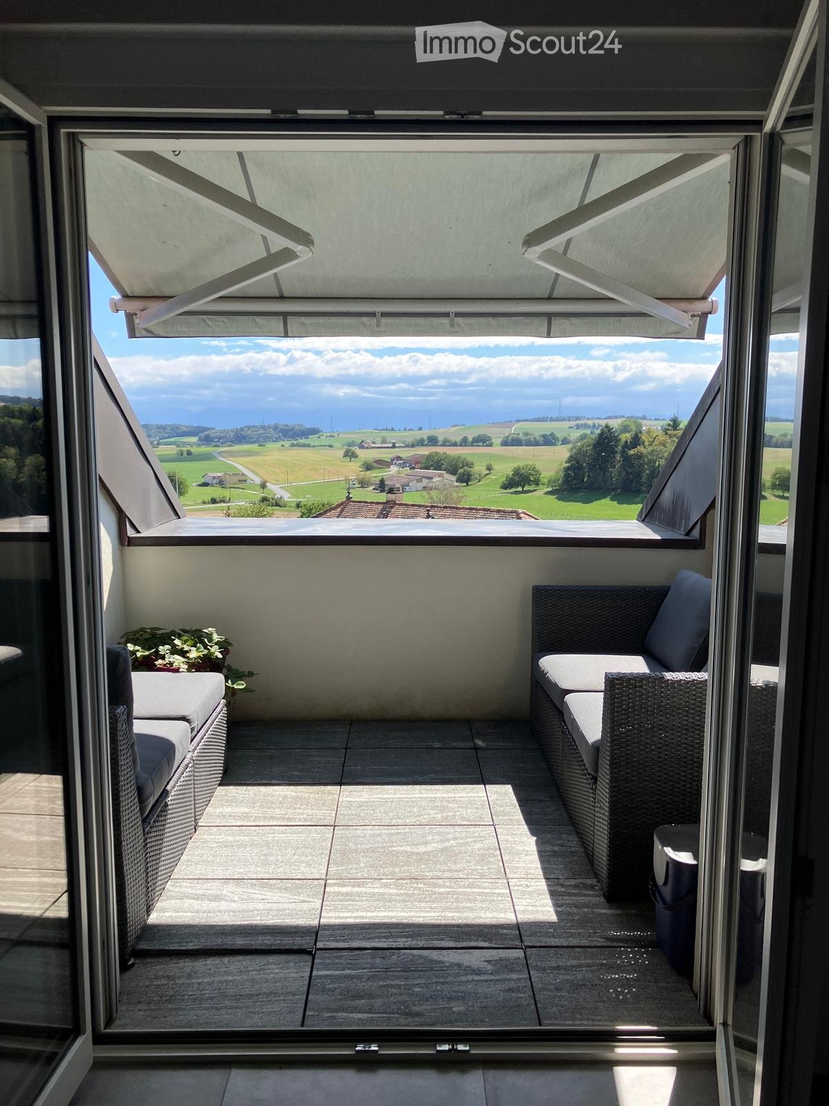 Balcony with wicker furniture, overlooking a scenic countryside view.