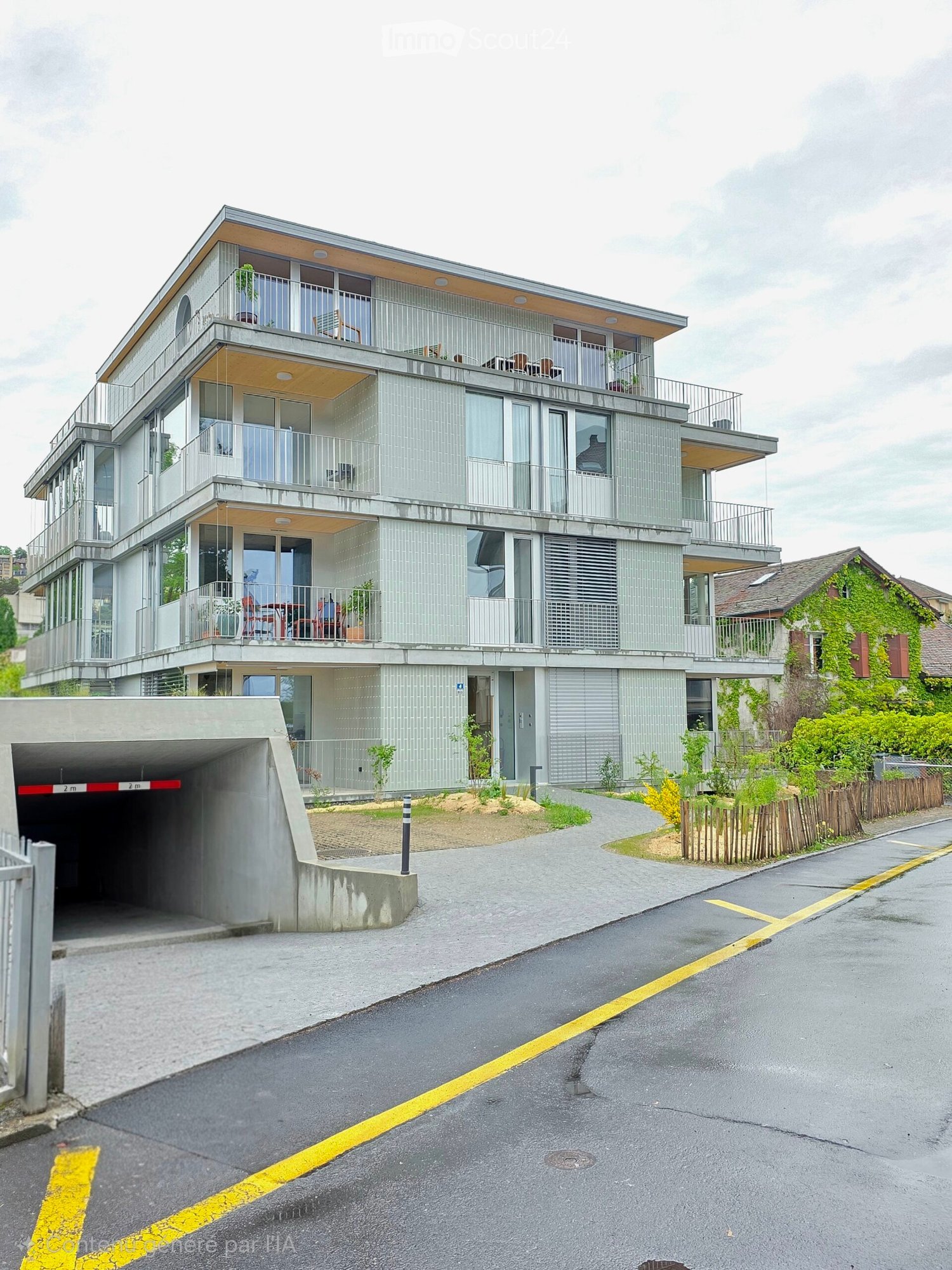 Modern multi-story building with balconies, large windows, and a covered garage entrance.