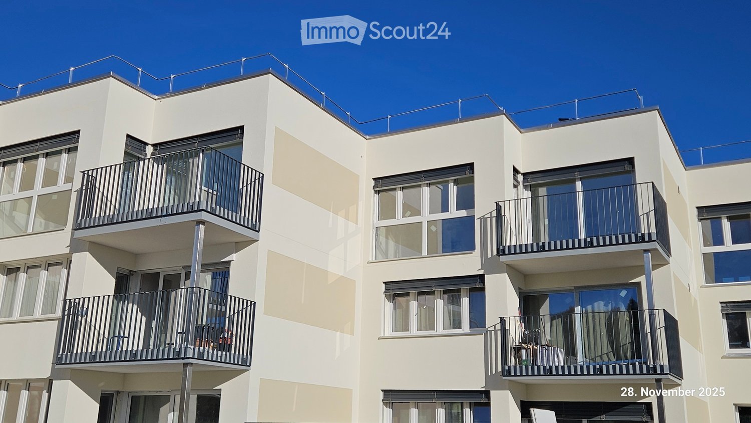 Modern 3-story building, beige facade, large glass windows, balconies on each floor