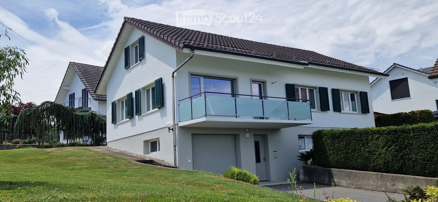 Two-story white house with a balcony, garage, and well-maintained lawn.