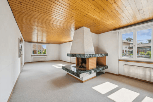 Empty room with wooden ceiling, fireplace, large windows, and light-colored carpeting.