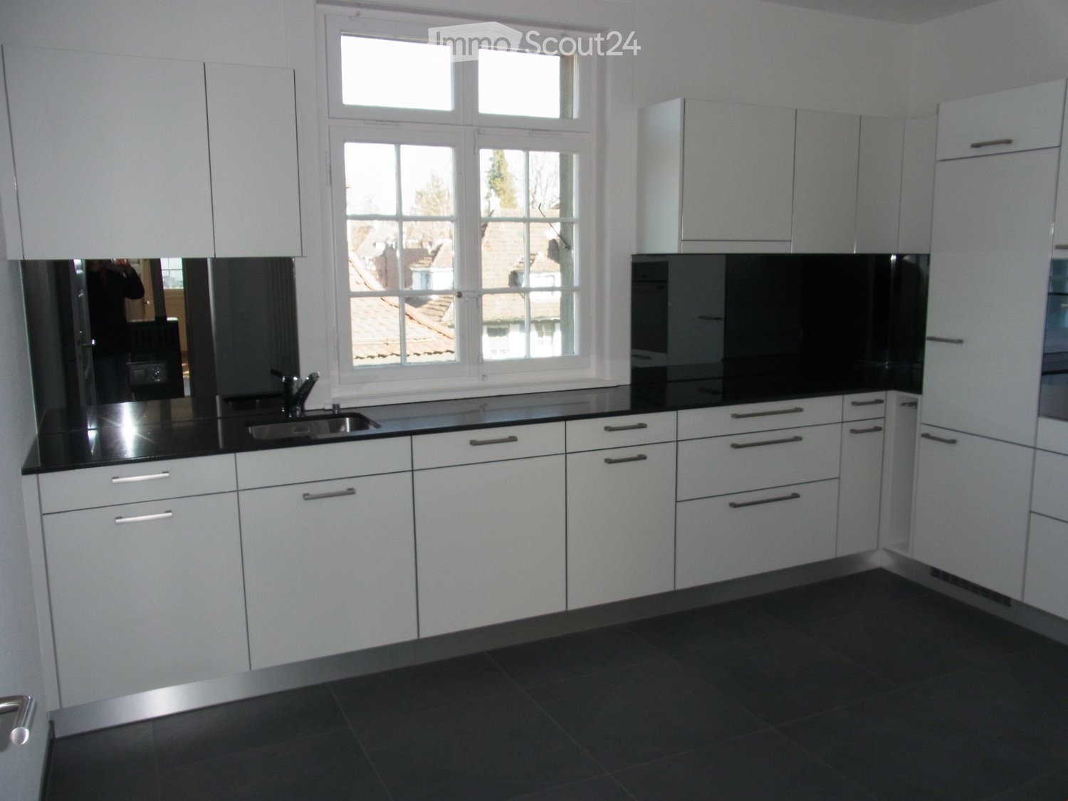 Modern kitchen with white cabinets, black countertops, and stainless steel sink and faucet.