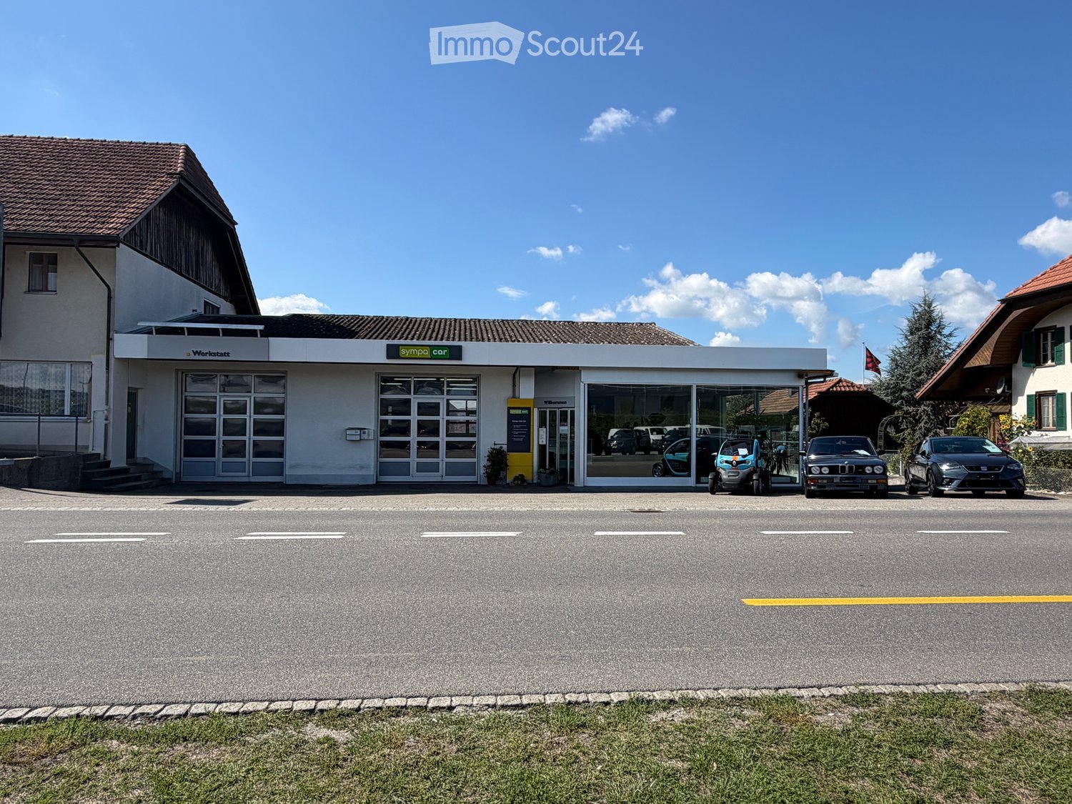 Car service center with a modern facade, large glass windows, and several cars parked in front.