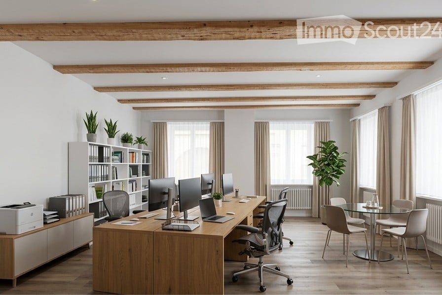 Modern office space with exposed wooden beams, large windows, office desk with multiple monitors, chairs, laptop, printer, bookshelf with books and plants, and a small round glass table with chairs.