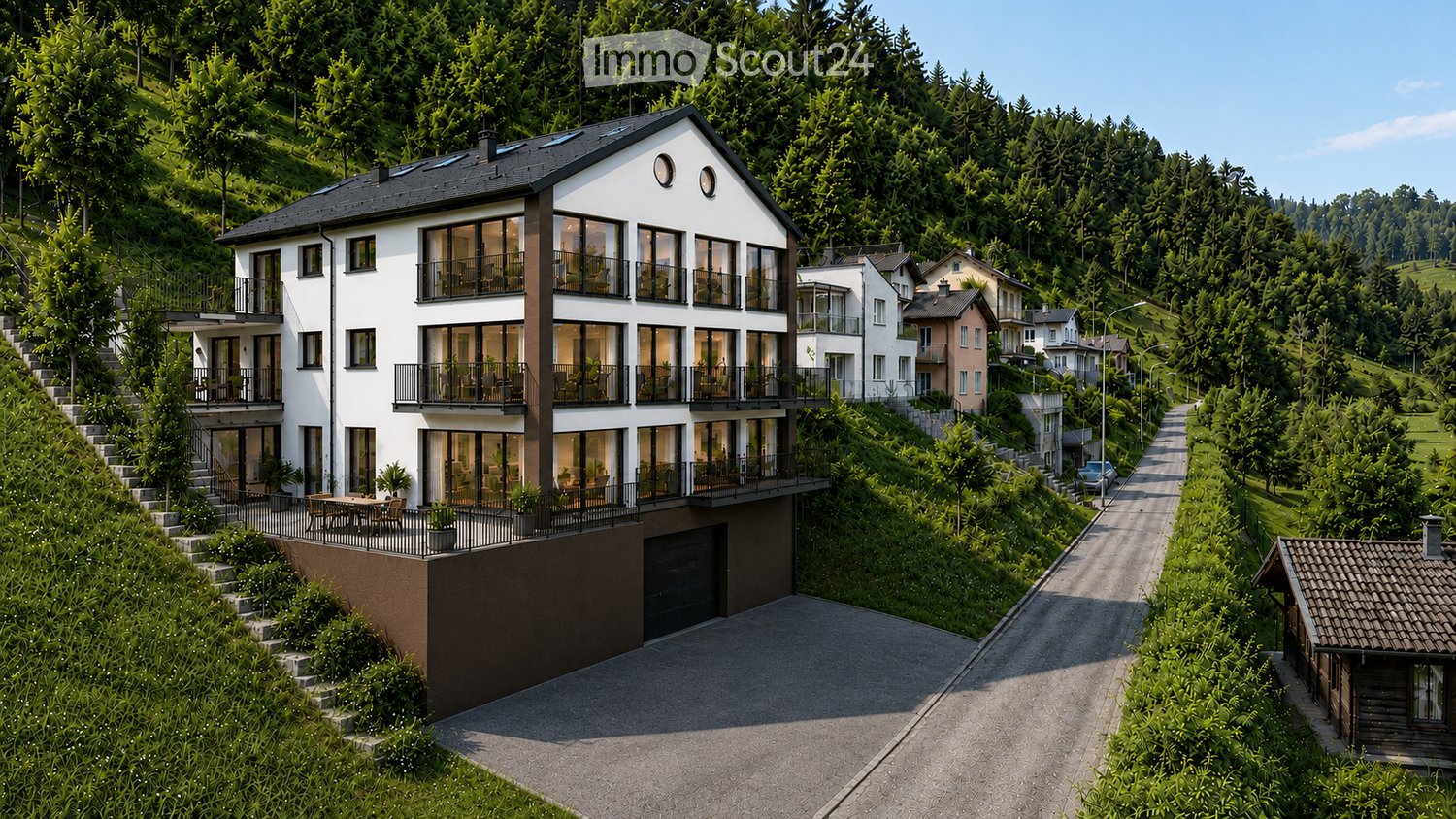 Modern two-story house with large windows and balconies, situated on a hillside with a scenic view of the surrounding forest and valley.