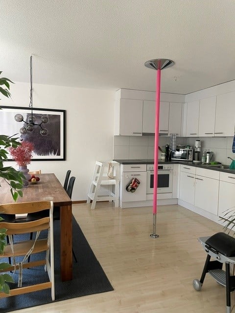 Open-plan kitchen and dining area with white cabinets, a wooden dining table, and modern appliances.