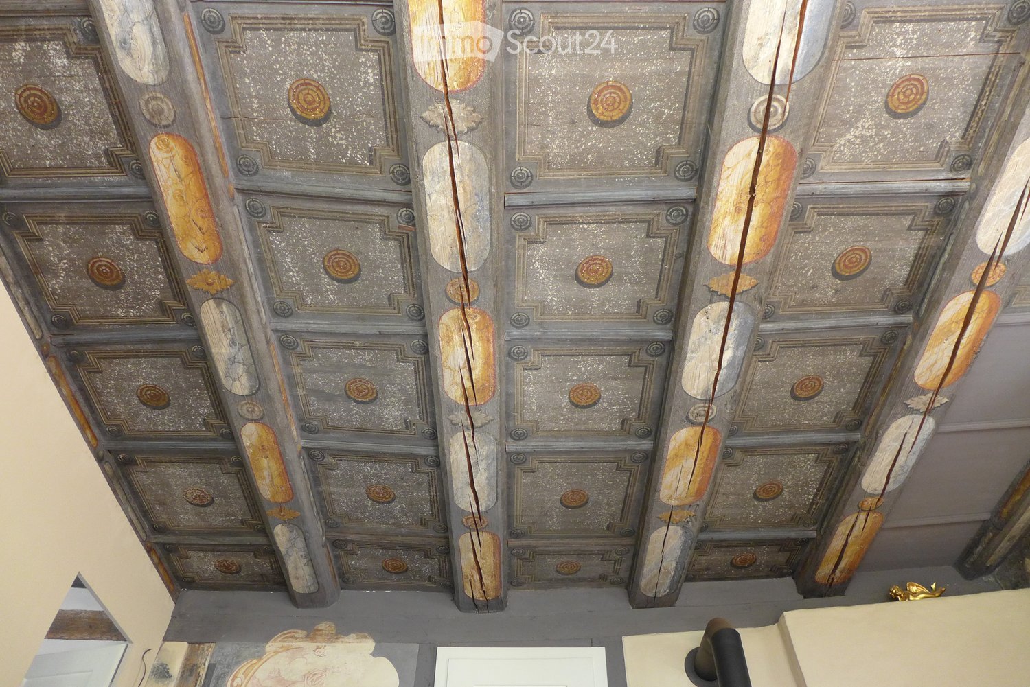 Ornate ceiling with intricate geometric and floral patterns, featuring metallic accents and decorative medallions.