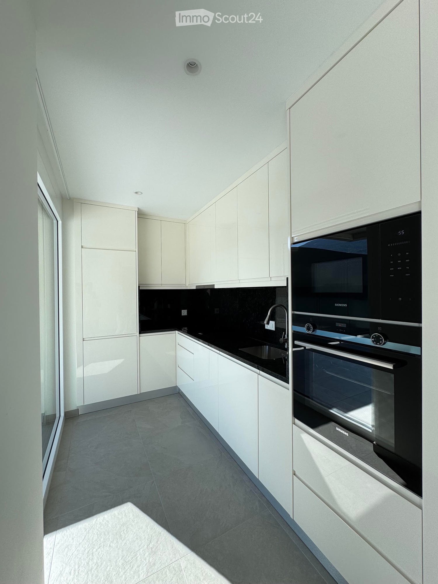 Modern kitchen with white cabinets, black countertop, stainless steel appliances, and a sleek design.