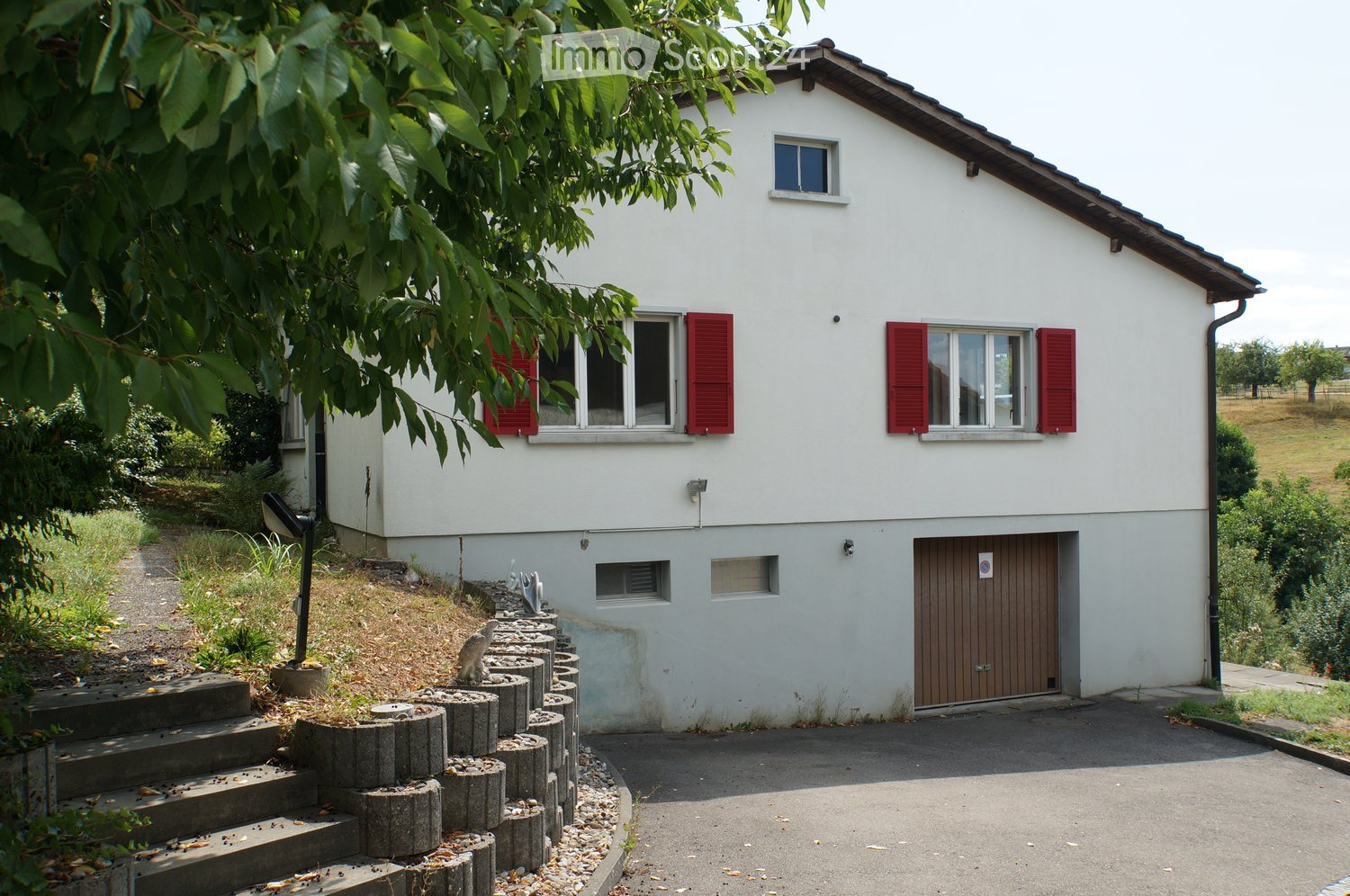 Two-story white house with red shutters, garage, and stone steps leading up to the entrance.
