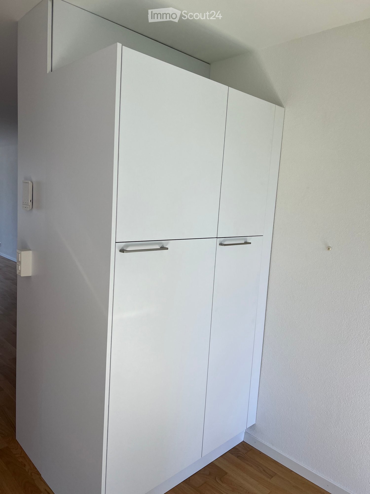 Empty room with white built-in cabinets and a wooden floor.