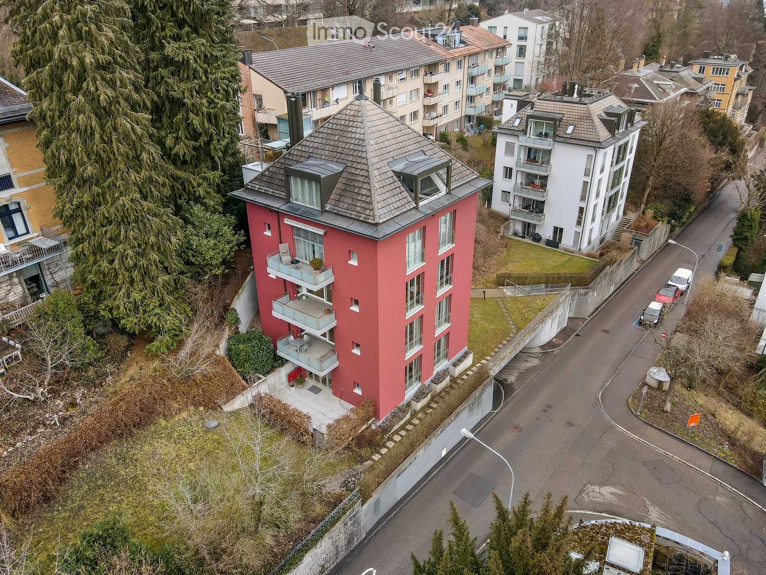 3-story red building with balconies and a gray roof