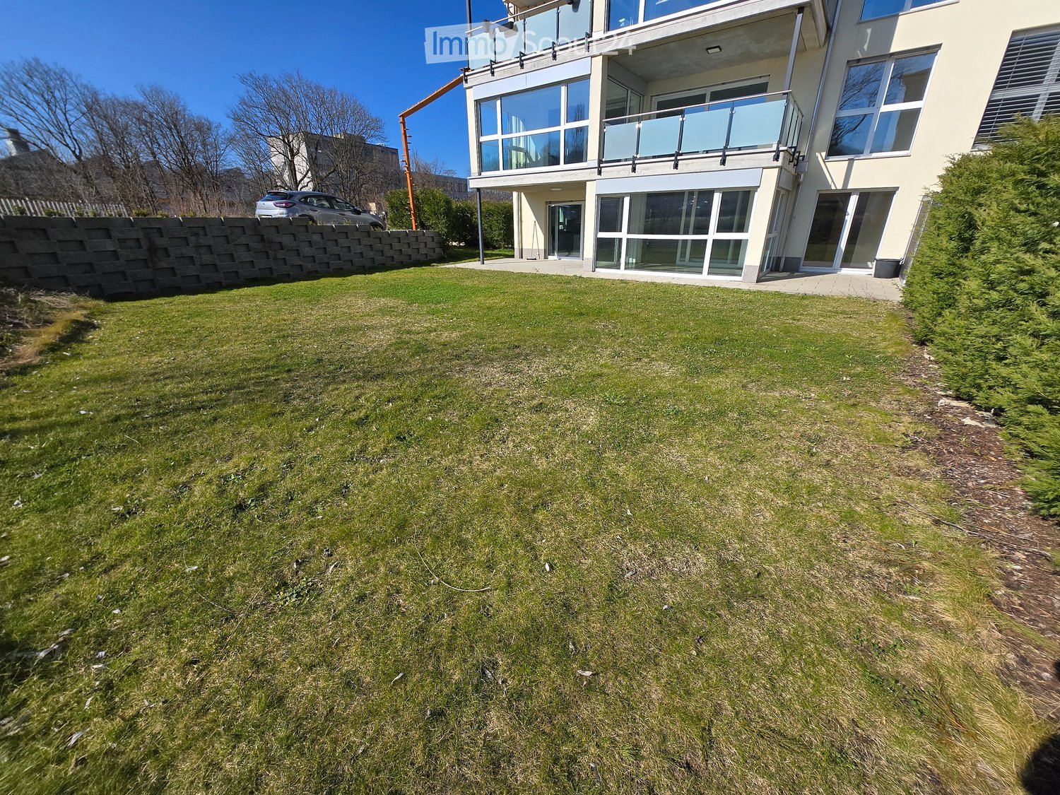 Lush green lawn in front of a modern two-story house with large windows and a balcony.