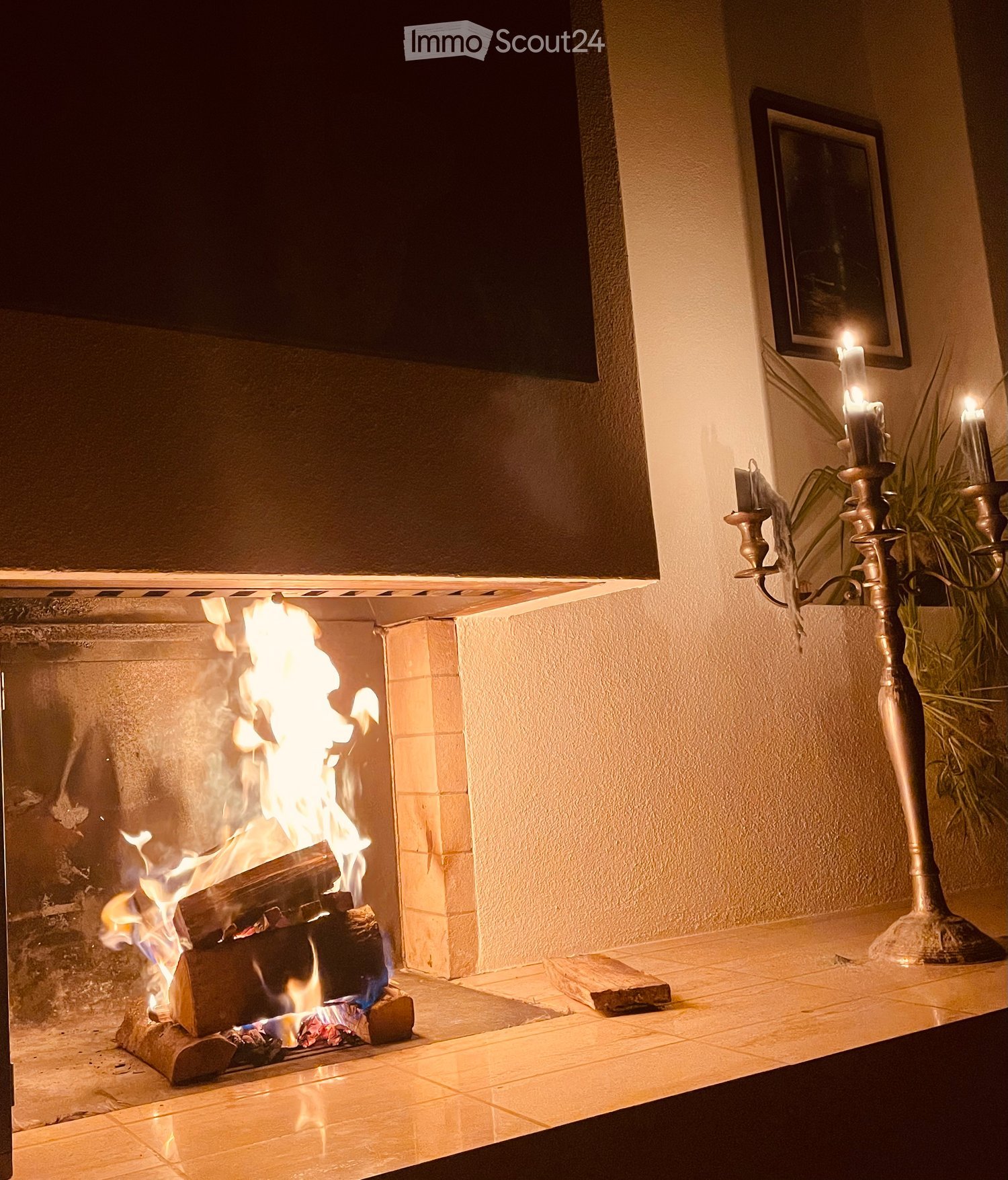 A modern living room with a lit fireplace, a candelabra, and a picture frame on the wall.