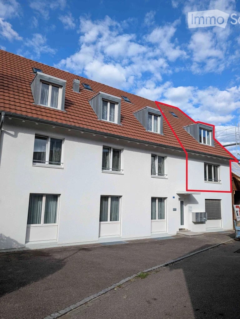 Two-story residential building with white walls, red-tiled roof, multiple windows, and a small balcony on the upper floor.