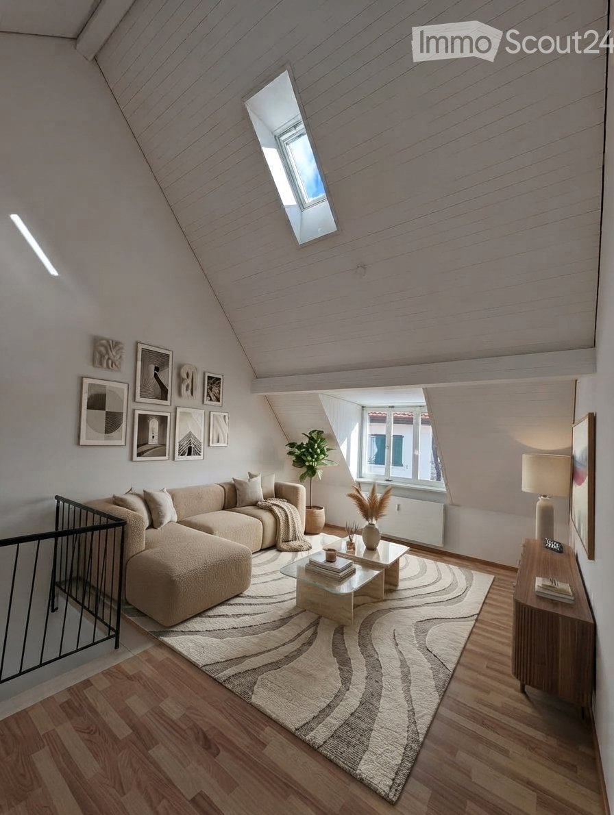 Modern living room with wooden flooring, a large sectional sofa, a glass coffee table, a side table with a lamp, and several picture frames on the wall.