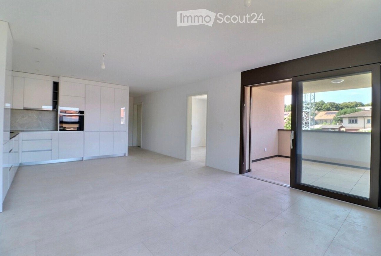 Empty room with tiled floor, white walls, and a sliding glass door leading to a balcony. The room has built-in kitchen cabinets and an oven on the left side.