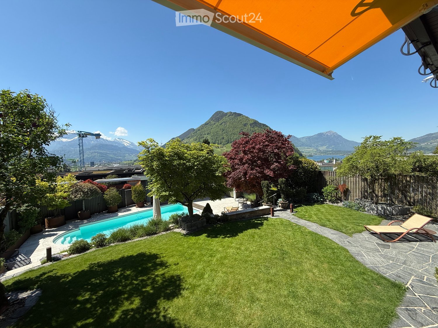 Well-maintained garden with a swimming pool, lounge chairs, and scenic mountain views.