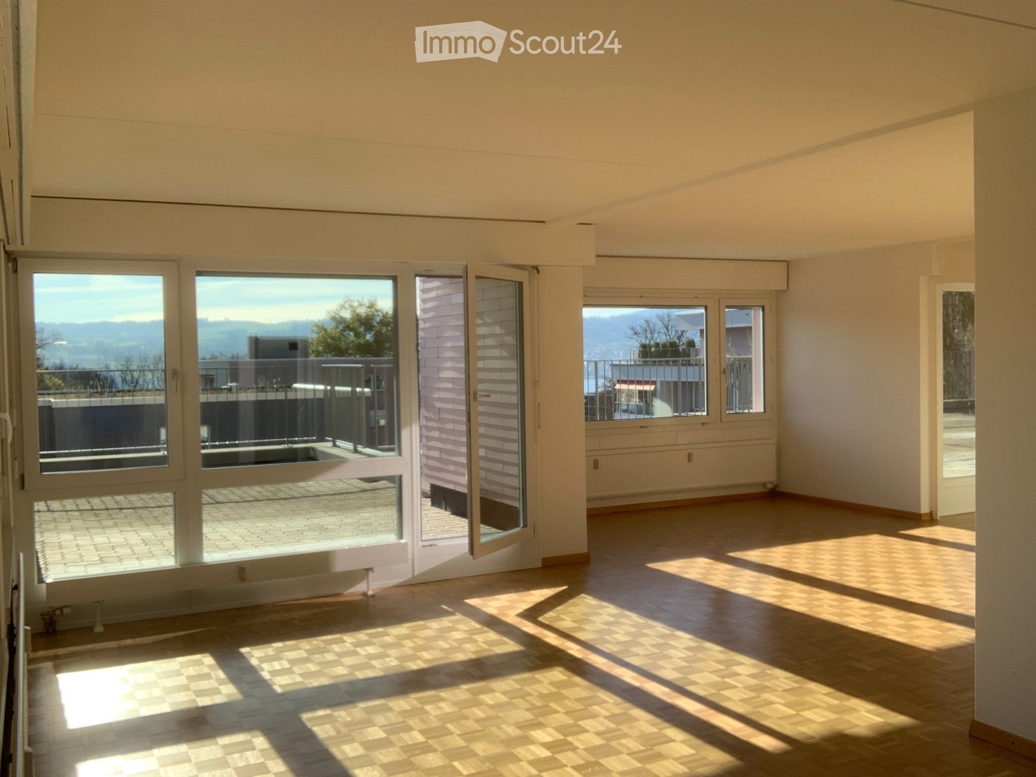 Empty room with wooden flooring, large windows, and a view of a balcony area. No furniture or equipment is present.
