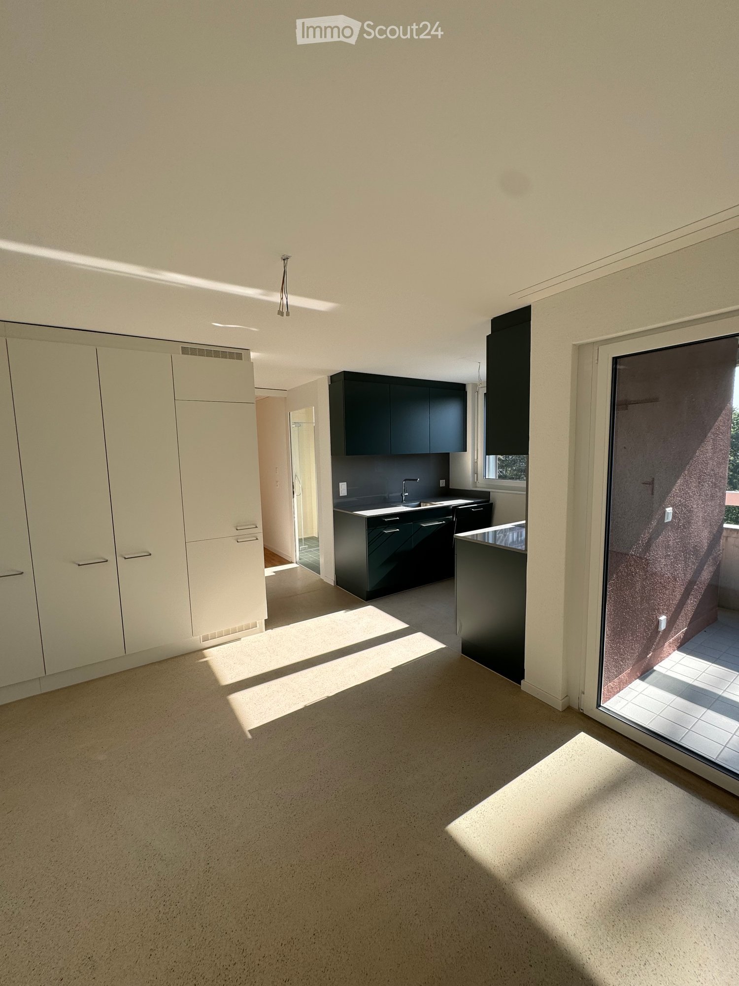 Modern kitchen with white and black cabinets, a sink, and a large window letting in natural light. The space is open and well-lit with a neutral color palette.
