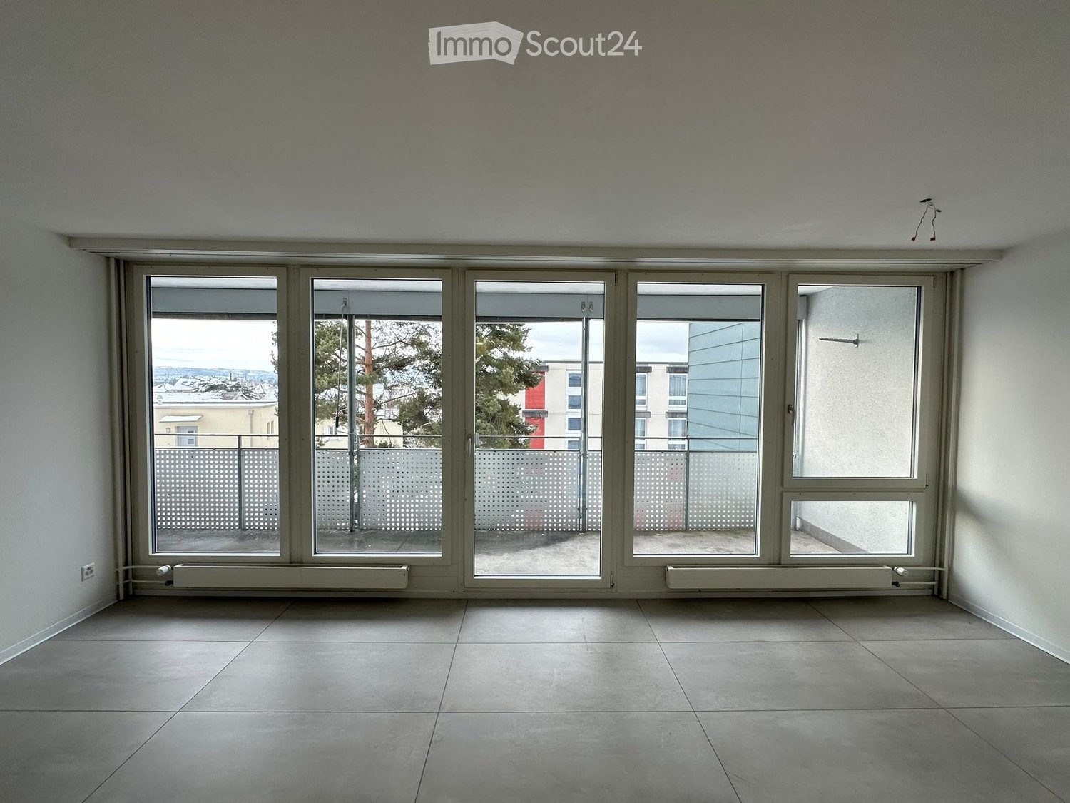 Empty room with large windows and tiled floor, no furniture or equipment.
