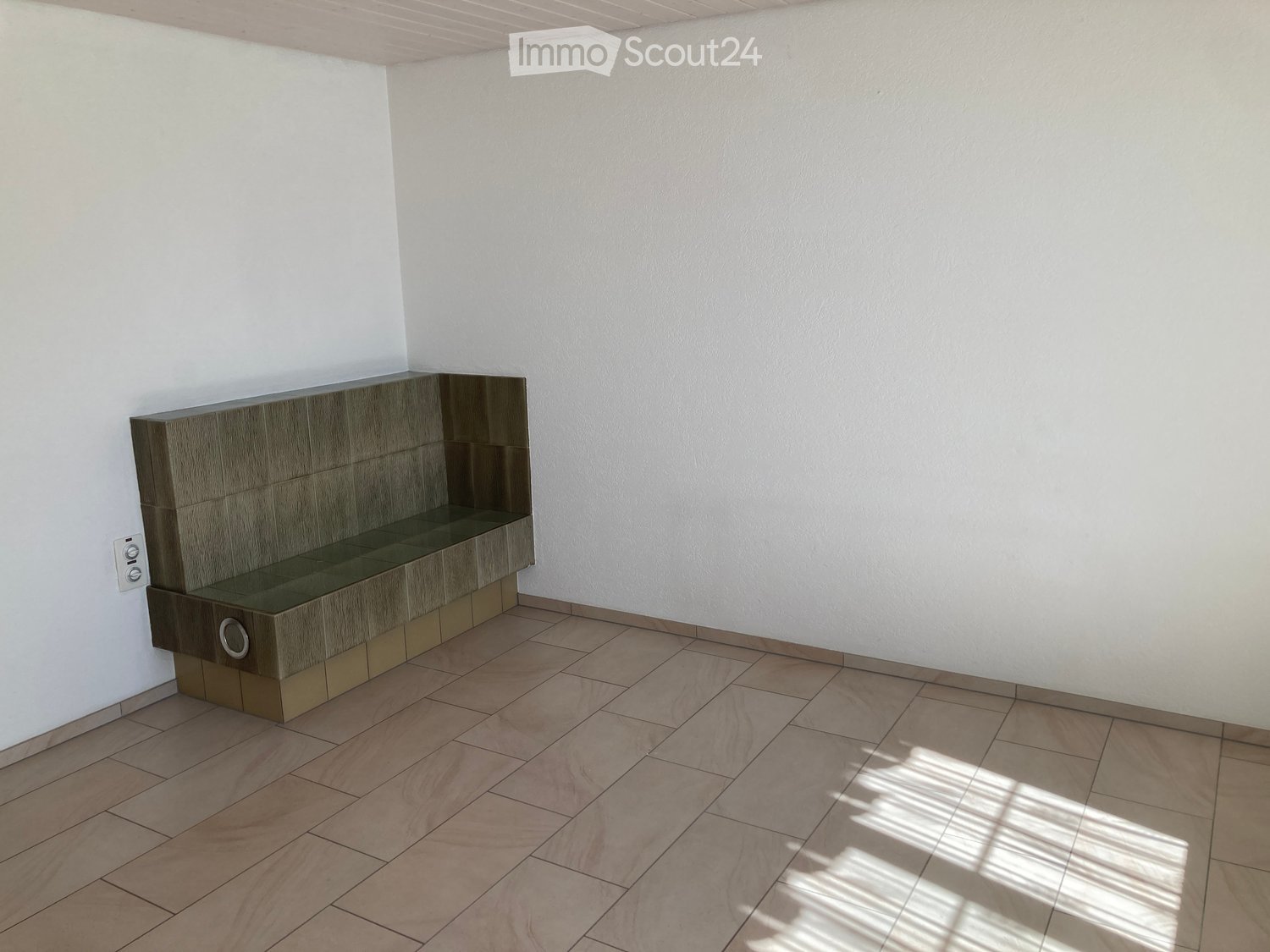 Empty room with light-colored walls, tiled floor, and a built-in bench along one wall.