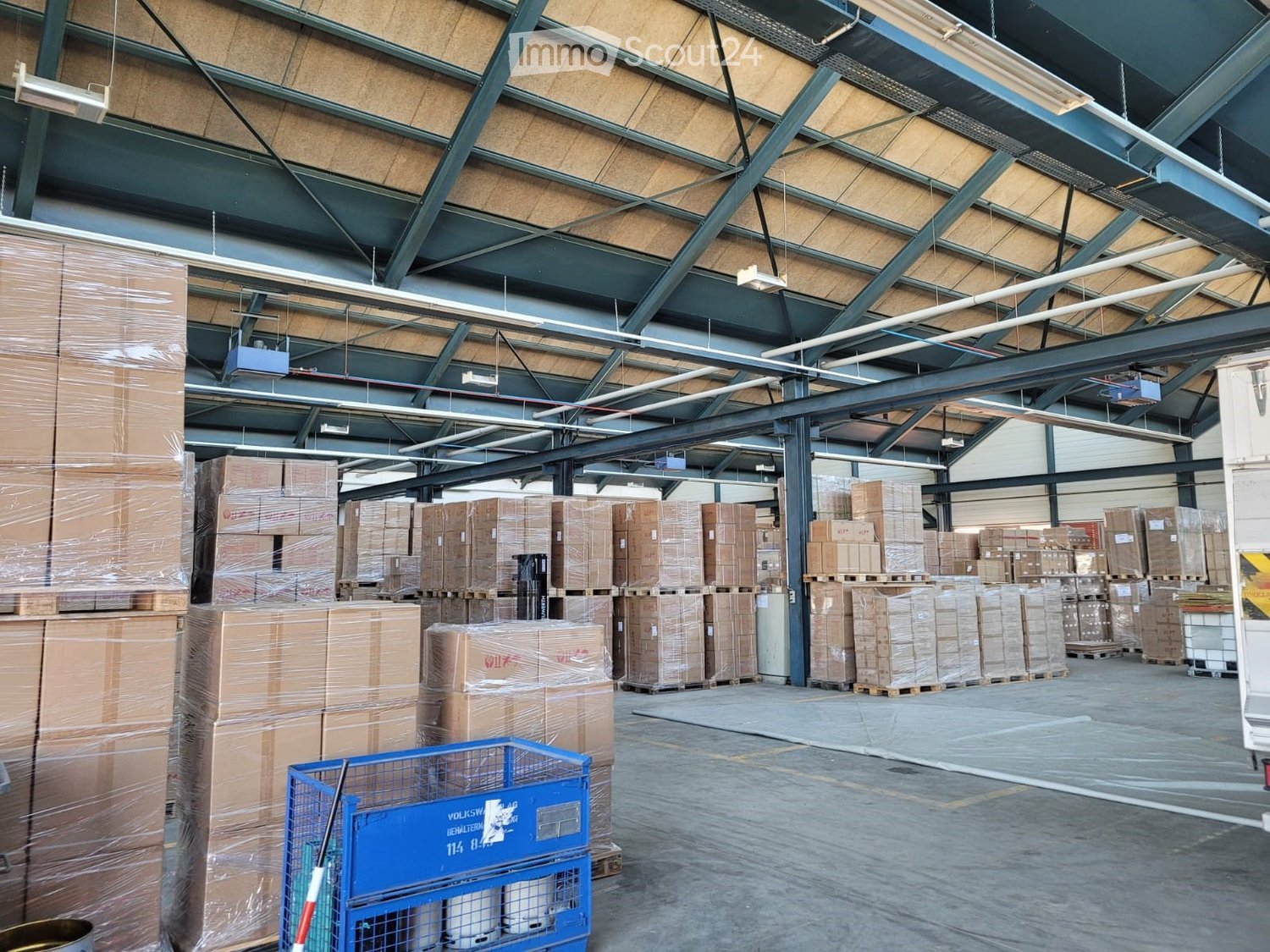 warehouse with high ceilings, multiple rows of storage boxes, forklift on the right, ceiling-mounted lights