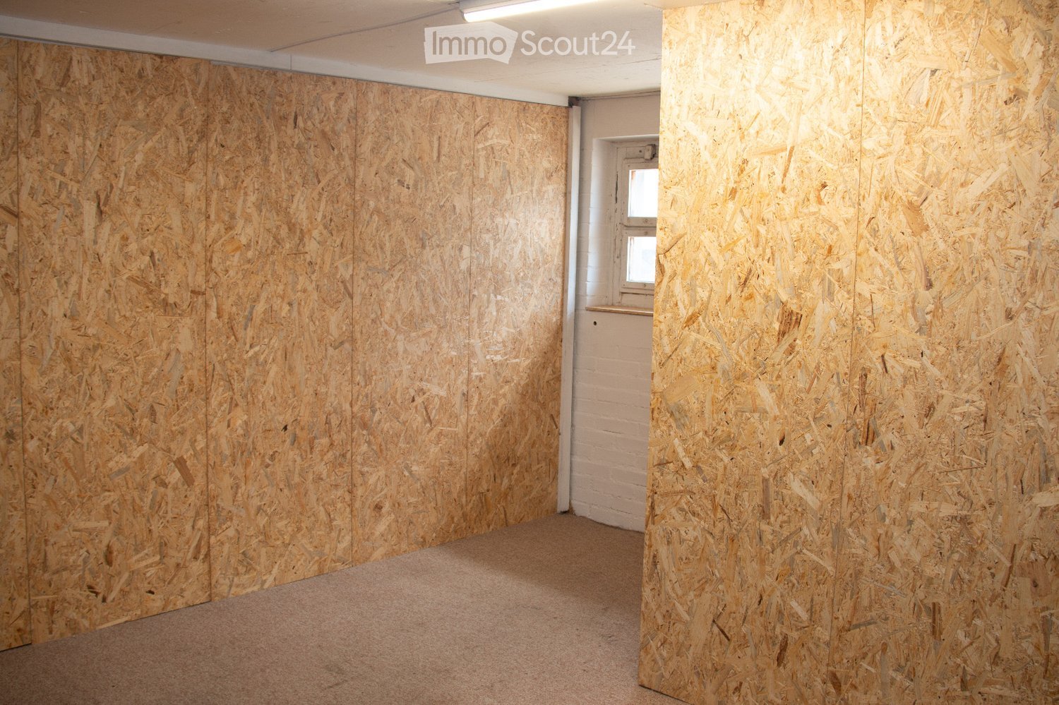 Empty room with bare walls covered in wood paneling and a carpeted floor. No furniture or equipment is present.