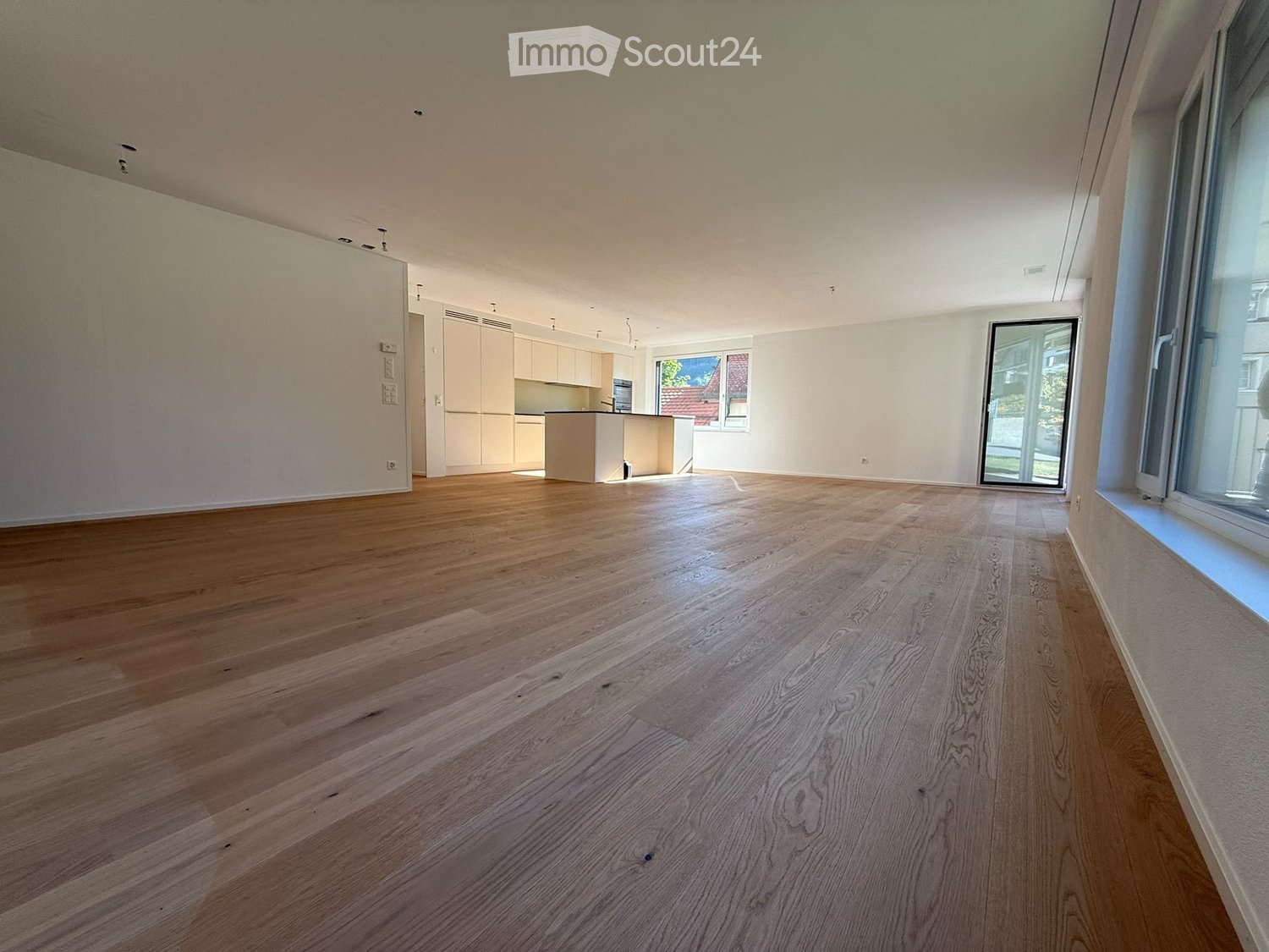 Empty room with wooden flooring, white walls, and large windows. No furniture or equipment present.