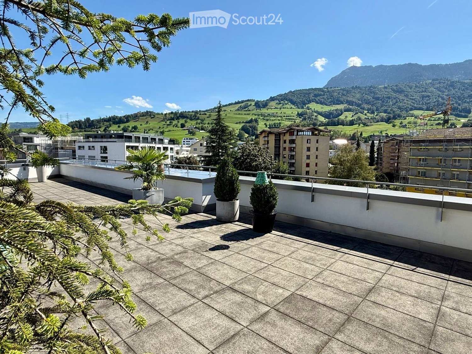 Roof terrace with tiled floor, potted plants, and a scenic mountain view in the background.