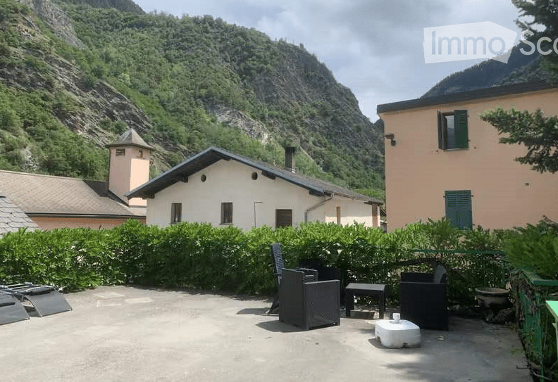 Outdoor patio with a scenic mountain view, featuring a few chairs, a small table, and a stool.